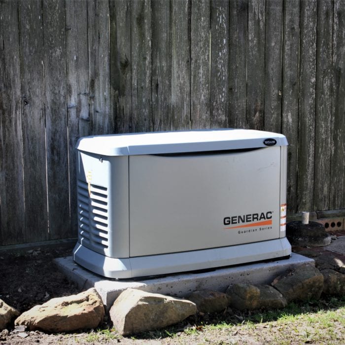A grey generator in the backyard of a home