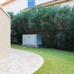 A large generac brand generator outside a home in a garden