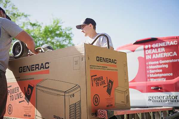 Two men picking up a generac brand generator box out of a truck